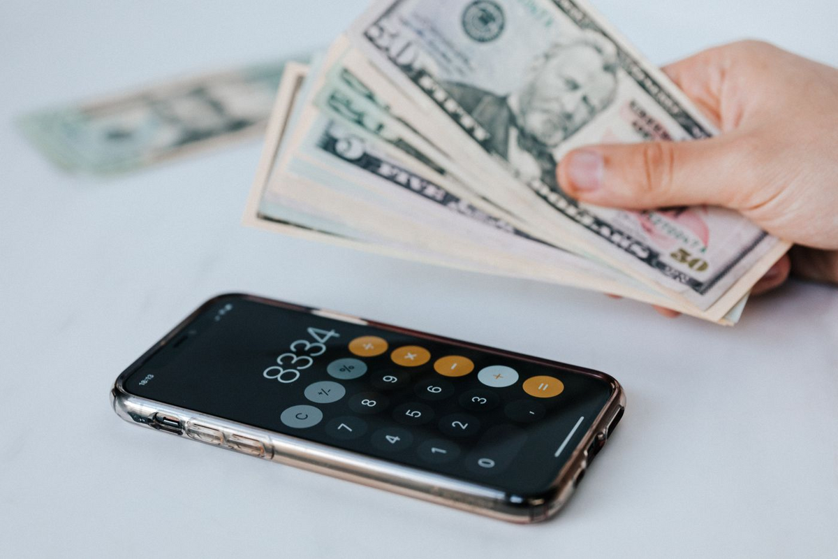 A phone beside a fan of US dollar bills.
